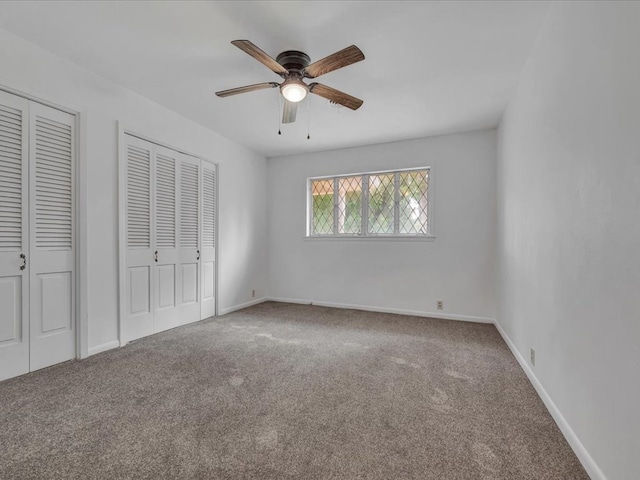 unfurnished bedroom with carpet, ceiling fan, and multiple closets