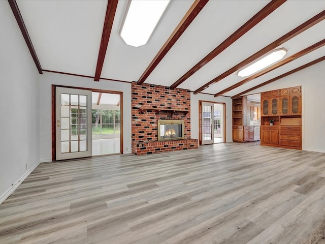 unfurnished living room featuring a brick fireplace, lofted ceiling with beams, and light hardwood / wood-style flooring