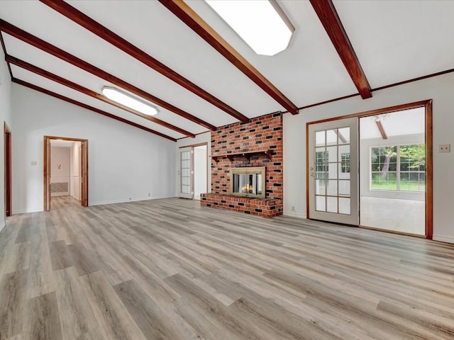 unfurnished living room with vaulted ceiling with beams, light hardwood / wood-style floors, and a brick fireplace