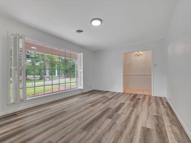 empty room featuring a chandelier and light hardwood / wood-style flooring