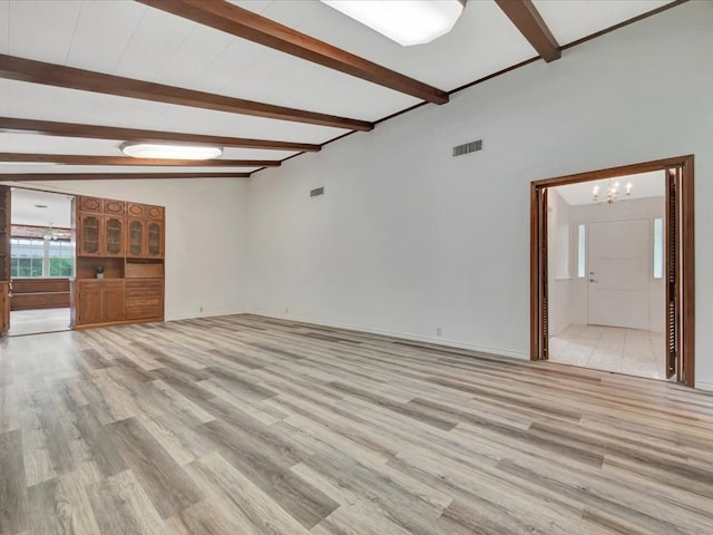 unfurnished living room with a notable chandelier, lofted ceiling with beams, and light wood-type flooring