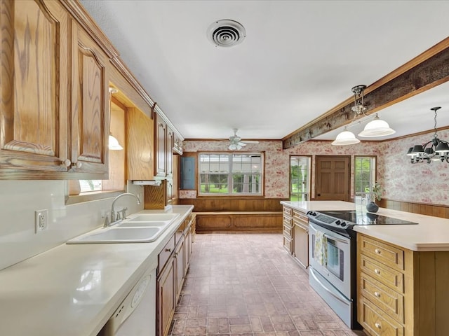 kitchen with white dishwasher, wooden walls, sink, electric stove, and decorative light fixtures