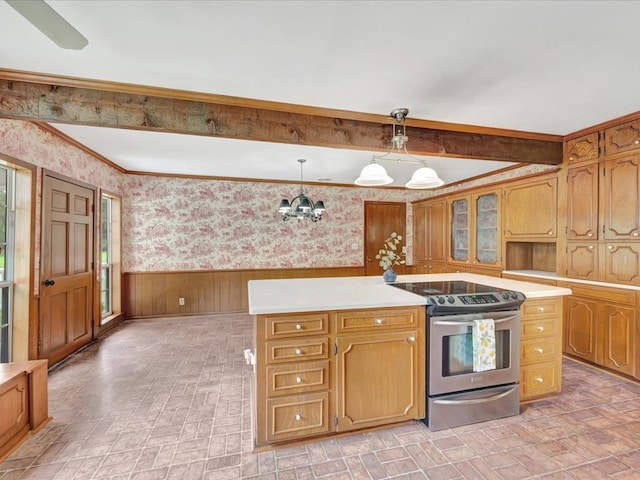 kitchen featuring pendant lighting, a chandelier, a kitchen island, stainless steel range with electric cooktop, and wood walls