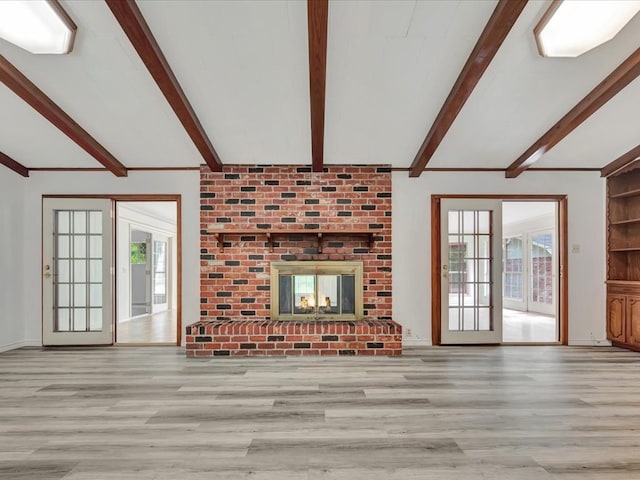 unfurnished living room featuring beamed ceiling, a fireplace, and light hardwood / wood-style flooring