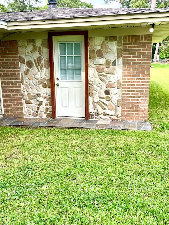 708 Card Dr, Lufkin, TX 75901 - entrance to property featuring stone siding, roof with shingles, a chimney, brick siding, and a lawn