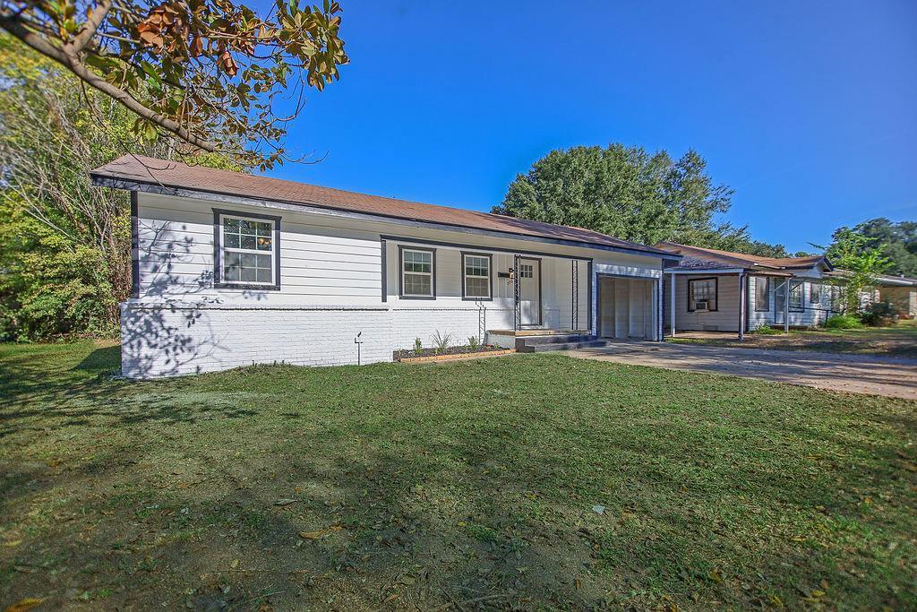 single story home featuring a garage and a front lawn