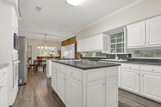 7332 Fm 252, Jasper, TX 75951 - kitchen featuring stainless steel appliances, a center island, decorative backsplash, white cabinetry, and ornamental molding