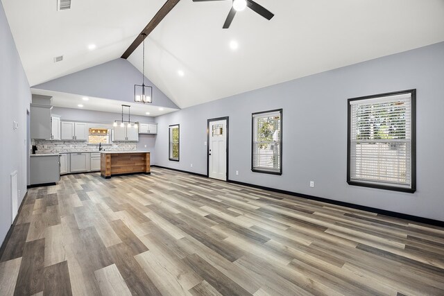 119 Park Pl, Lufkin, TX 75901 - unfurnished living room with a ceiling fan, beam ceiling, light wood-style floors, a chandelier, and recessed lighting