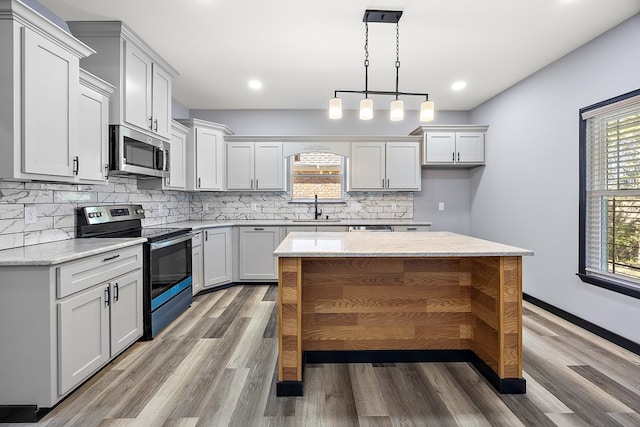 kitchen featuring a center island, sink, stainless steel appliances, light stone counters, and hardwood / wood-style floors