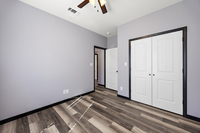 unfurnished bedroom with ceiling fan, dark hardwood / wood-style floors, and a closet