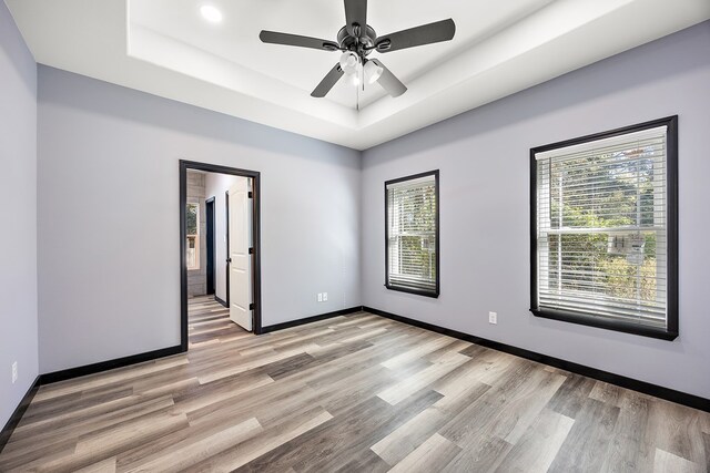 unfurnished room featuring a tray ceiling, light hardwood / wood-style flooring, and ceiling fan