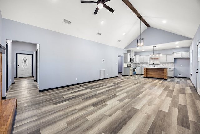 unfurnished living room with beamed ceiling, high vaulted ceiling, wood-type flooring, and ceiling fan with notable chandelier