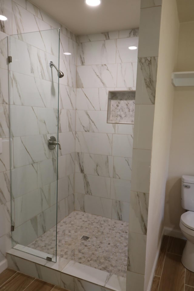 bathroom featuring a tile shower and toilet