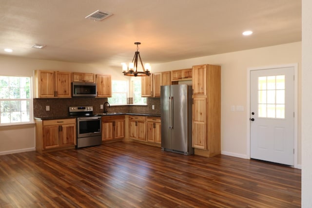 kitchen featuring sink, hanging light fixtures, dark wood-type flooring, stainless steel appliances, and a notable chandelier