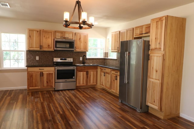 kitchen with dark hardwood / wood-style flooring, stainless steel appliances, sink, a notable chandelier, and hanging light fixtures