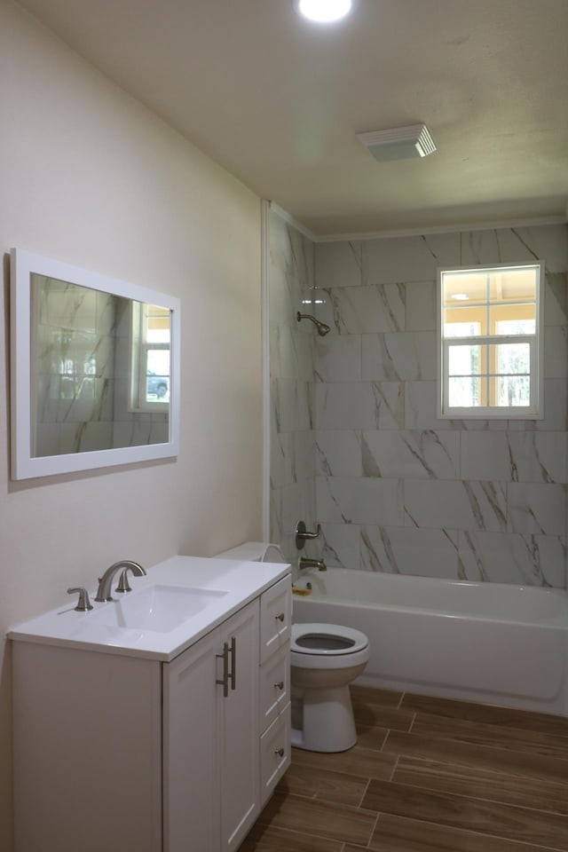 full bathroom featuring hardwood / wood-style floors, vanity, toilet, and tiled shower / bath