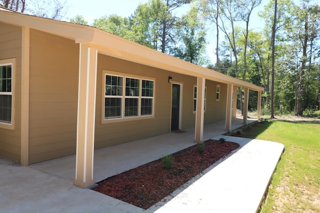 doorway to property featuring a lawn and a patio