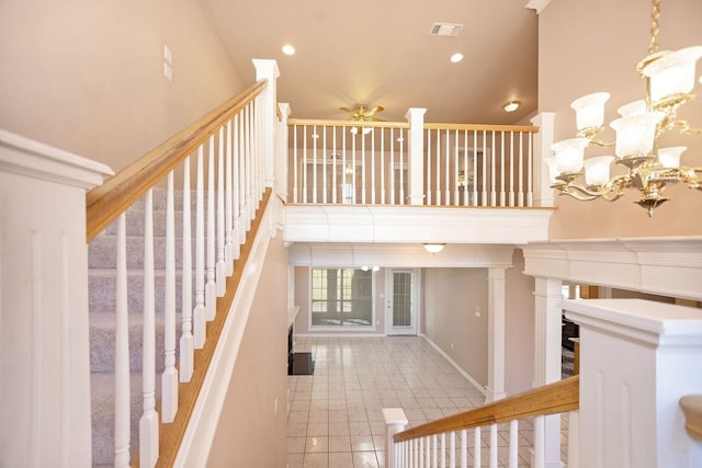 stairs featuring a towering ceiling, ceiling fan with notable chandelier, and tile patterned floors