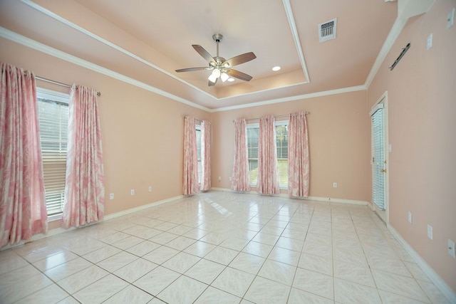 unfurnished room with light tile patterned flooring, a wealth of natural light, crown molding, and a tray ceiling