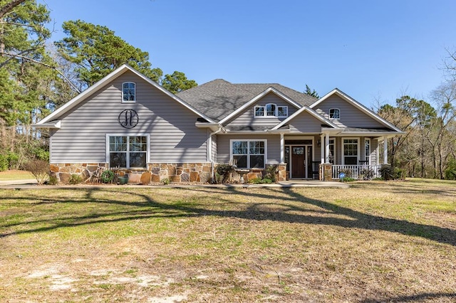 craftsman inspired home with stone siding, a porch, roof with shingles, and a front yard