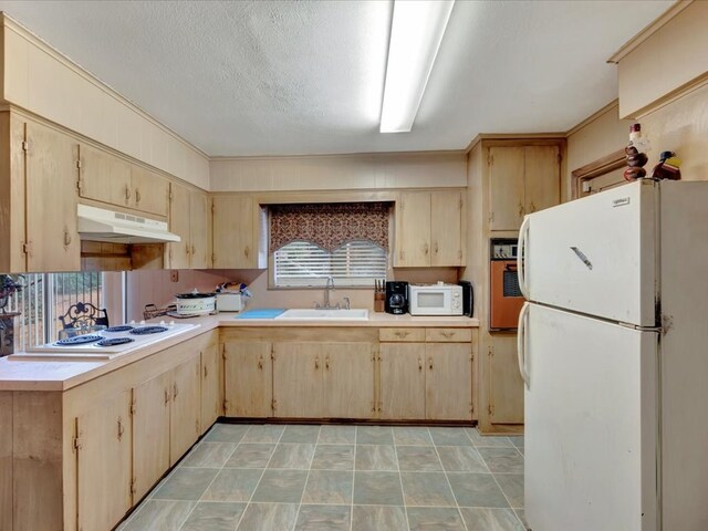 kitchen featuring a textured ceiling, light brown cabinets, white appliances, and sink