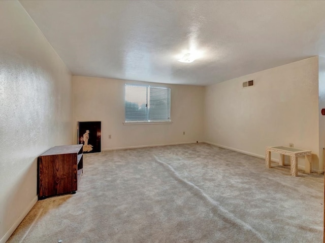 unfurnished room with light colored carpet and a textured ceiling