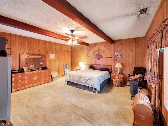 bedroom with light carpet, a textured ceiling, ceiling fan, beamed ceiling, and wood walls