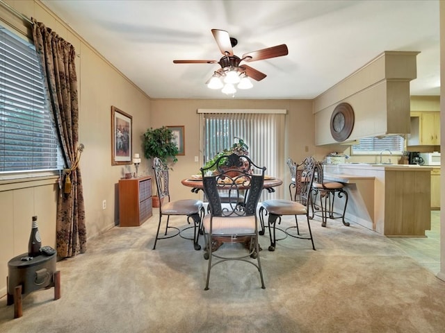 dining area with light colored carpet, ceiling fan, ornamental molding, and sink