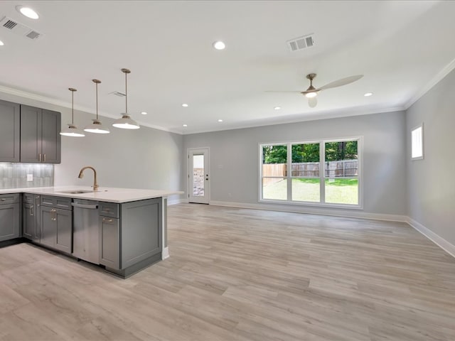 kitchen featuring ceiling fan, sink, dishwasher, hanging light fixtures, and light wood-type flooring