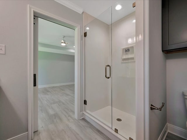 bathroom with hardwood / wood-style flooring, ceiling fan, toilet, ornamental molding, and a shower with shower door