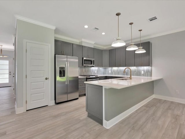 kitchen with kitchen peninsula, light hardwood / wood-style flooring, pendant lighting, and appliances with stainless steel finishes