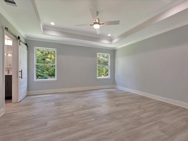 unfurnished bedroom featuring light wood-type flooring, a barn door, and multiple windows