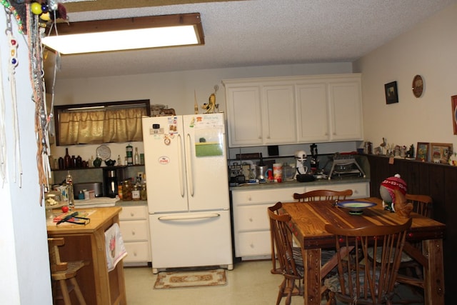 kitchen featuring white fridge, white cabinetry, and a textured ceiling