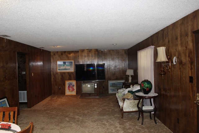 carpeted living room featuring wood walls and a textured ceiling