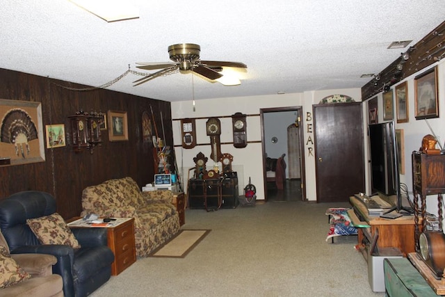 carpeted living room with wooden walls, ceiling fan, and a textured ceiling