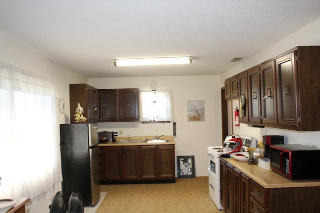 kitchen with white range with electric cooktop, stainless steel fridge, a healthy amount of sunlight, and a textured ceiling