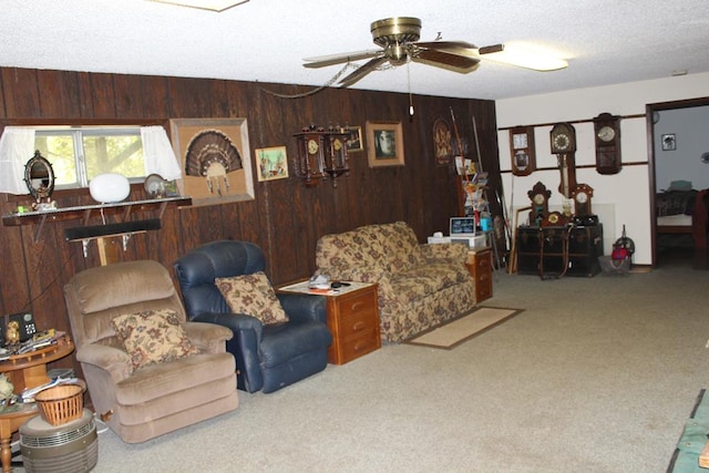 carpeted living room featuring wooden walls, ceiling fan, and a textured ceiling