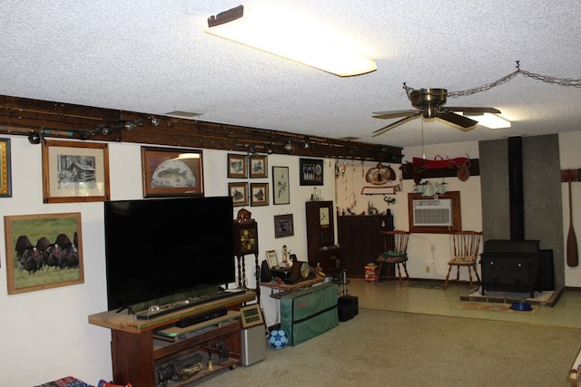 living room featuring ceiling fan, a wood stove, and a textured ceiling