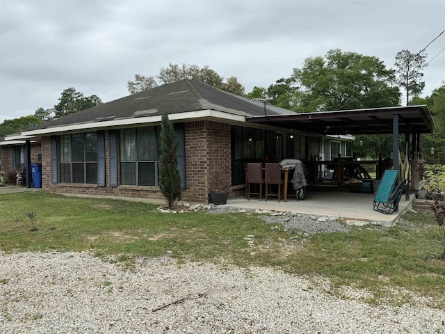 back of property featuring a yard, brick siding, and a patio area