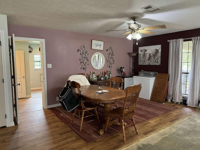 dining space featuring visible vents, a ceiling fan, a textured ceiling, wood finished floors, and baseboards