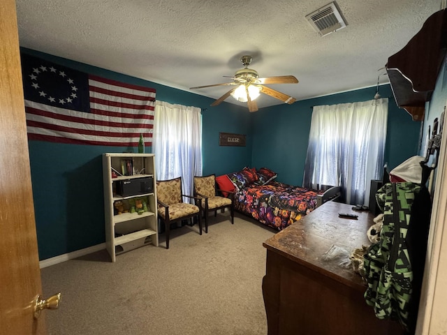 carpeted bedroom featuring a ceiling fan, visible vents, a textured ceiling, and baseboards