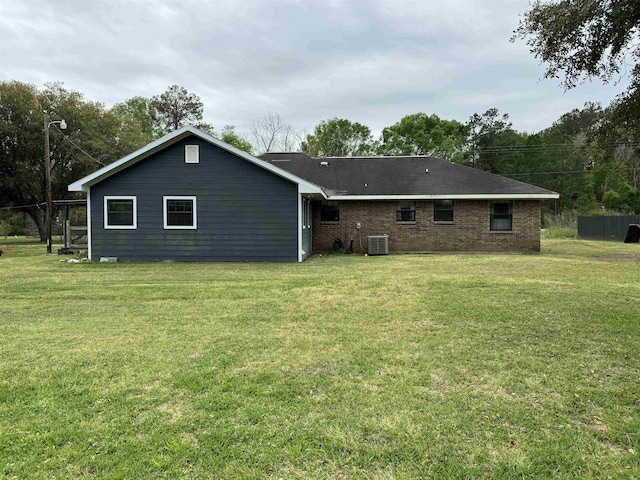 back of property featuring brick siding, a lawn, and central AC unit