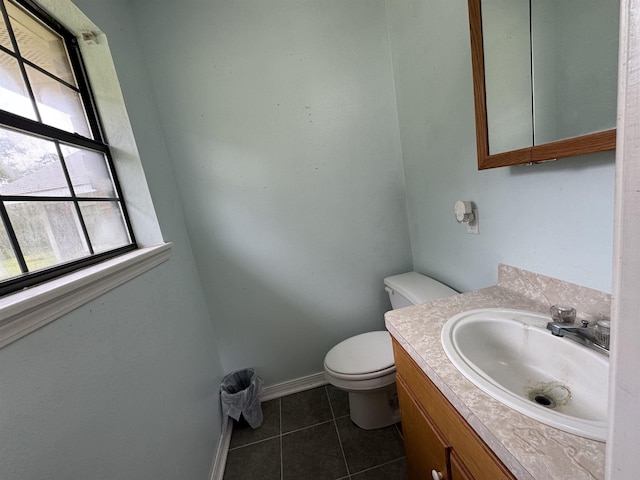 half bath featuring toilet, vanity, baseboards, and tile patterned floors