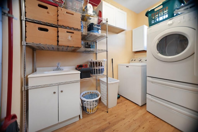 laundry area with cabinet space, a sink, and light wood finished floors
