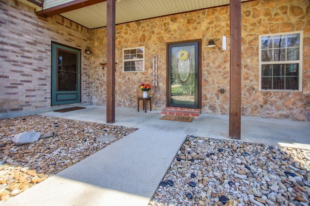 view of exterior entry with a porch and stone siding
