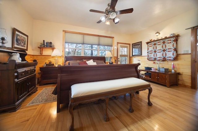 bedroom featuring wood walls, a wainscoted wall, and light wood-style floors