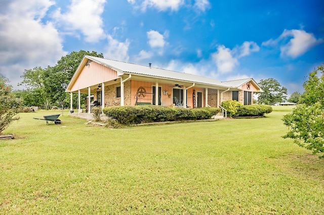 back of house with a lawn, a ceiling fan, brick siding, and metal roof