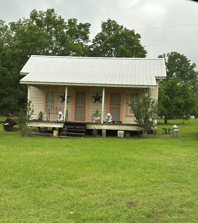 view of front of home featuring covered porch, metal roof, and a front lawn