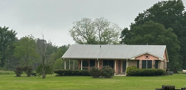 view of front facade featuring metal roof, cooling unit, and a front lawn