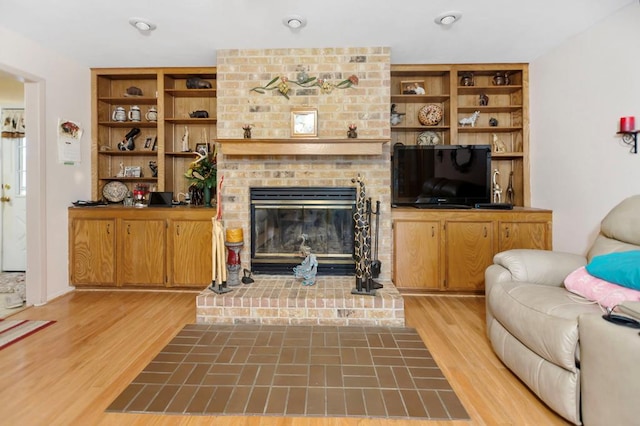 living area with a brick fireplace and light wood-style flooring